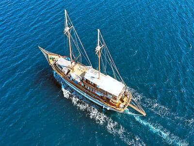 Segelurlaub in Griechenland: Eine Yacht segelt vor der Kulisse malerischer Inseln mit türkisfarbenem Wasser und strahlend blauem Himmel in der Ägäis