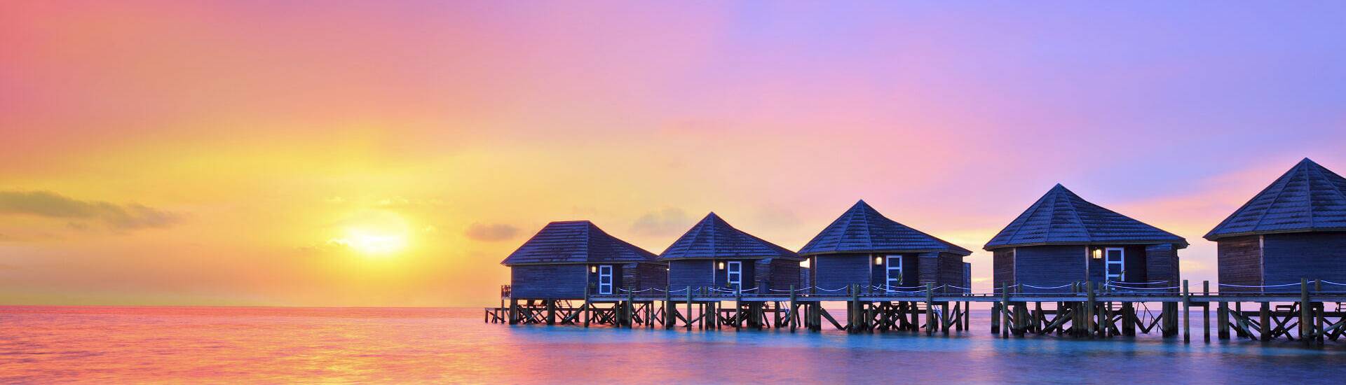 Wasserbungalows auf den Malediven mit Blick auf das türkisfarbene Meer und weißen Sandstrand.