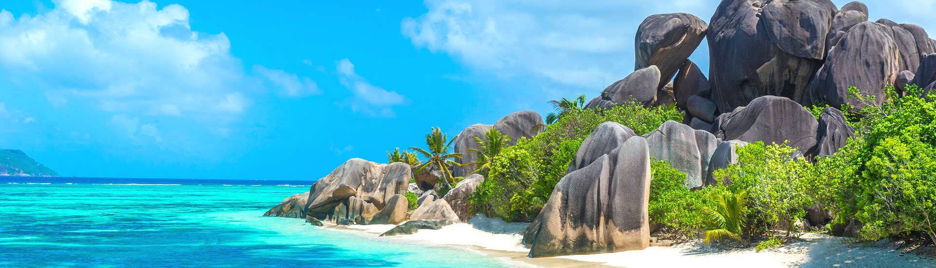 Seychellen Strand mit türkisfarbenem Wasser, Palmen und Sonnenschein - Beste Reisezeit Seychellen.