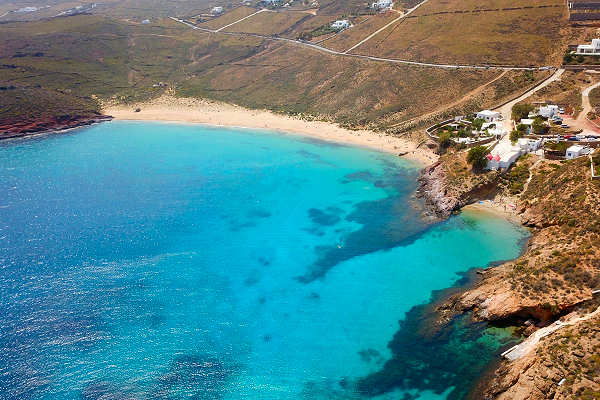 Ruhiger Strand Agios Sostis auf Mykonos, Griechenland, mit kristallklarem Wasser und goldenen Sand, ideal für einen erholsamen Urlaub.