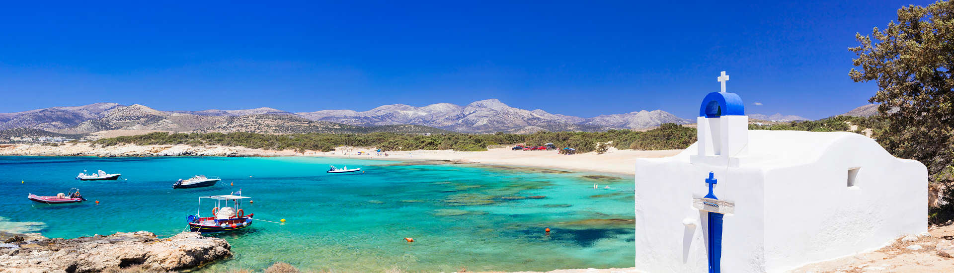 Malerische Bucht auf Naxos mit klarem Wasser und einer traditionellen weißen Kapelle am Strand