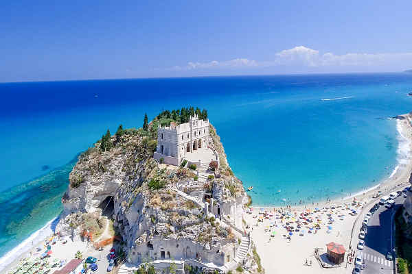 Küstenblick auf das malerische Tropea in Kalabrien, Italien, mit strahlend blauem Meer und historischen Gebäuden auf den Klippen.