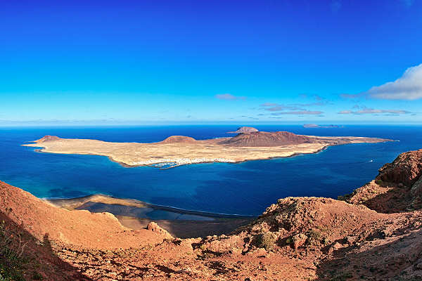 Panoramablick auf die Insel La Graciosa während eines Lanzarote Urlaubs, umgeben von türkisblauem Meer.