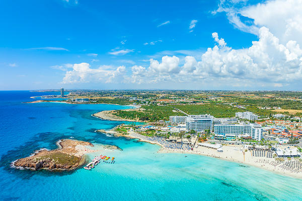 Küste Zyperns mit türkisblauem Wasser und sonnigem Himmel, ideal für einen erholsamen Urlaub.