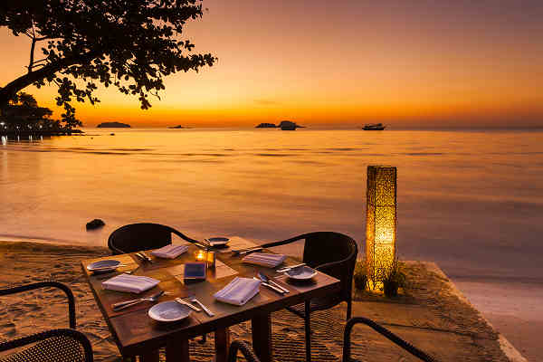 Bild vom Abendessen am Strand in einem romantischen Restaurant in Phuket, Thailand, während die Sonne untergeht