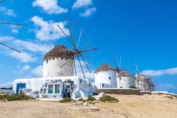 Blick auf die berühmten Windmühlen und das kristallklare Wasser von Mykonos, Griechenland.  Titel: Griechenland Reisen: Entdecke das lebhafte Mykonos - Strände, Kultur & Nachtleben.