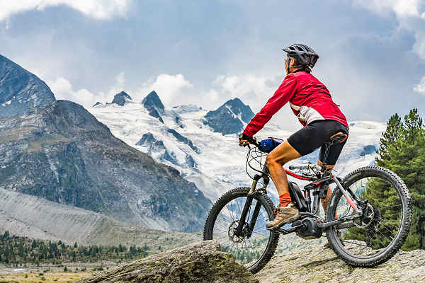 Mountainbiker genießt eine Fahrt auf einem malerischen Alpenpfad in der Schweiz mit atemberaubender Bergkulisse.