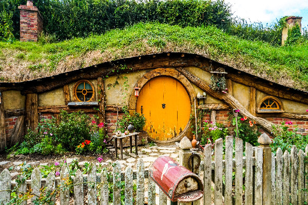 Charmantes Hobbit-Haus in der grünen Landschaft Neuseelands, ein Highlight der Ozeanien Reisen