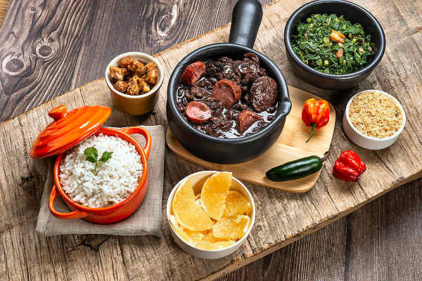 Traditionelle brasilianische Feijoada, serviert in einer rustikalen Schüssel, begleitet von Reis und Orangenstücken